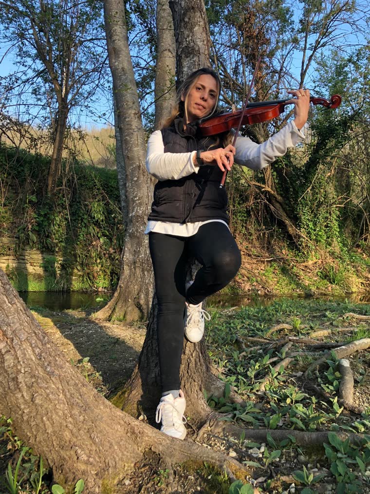 Montse Tudela tocando el violín en plena naturaleza